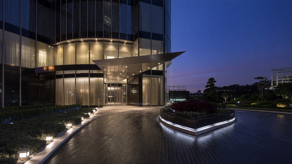 Entrance forecourt at night - canopy, bollards, lit planter and landscape