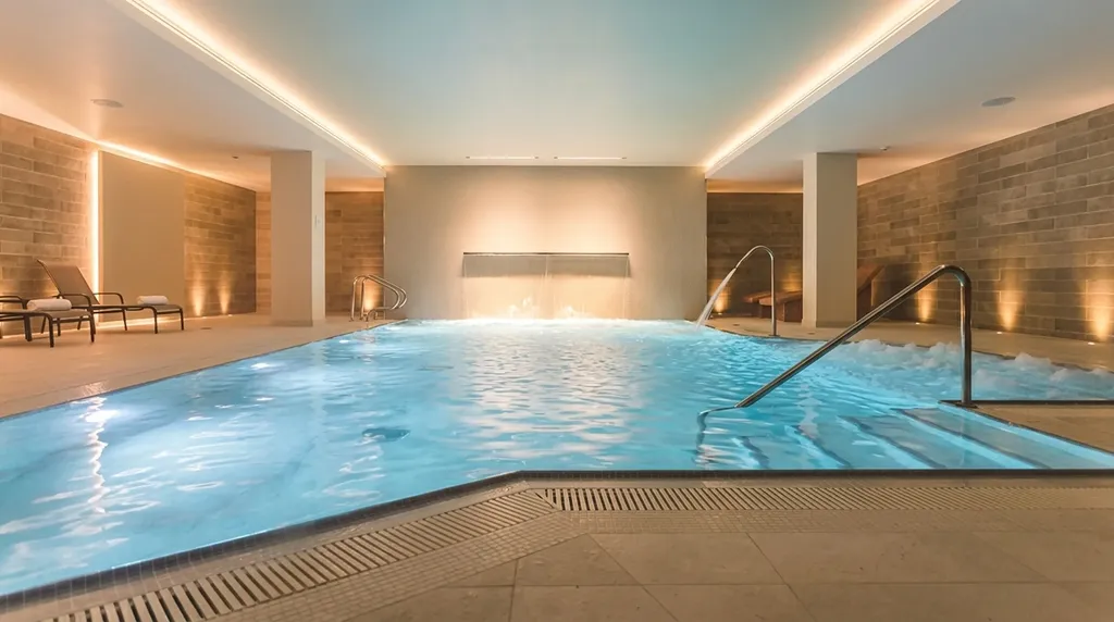 Spa pool - perimeter ceiling cove, stone wall grazing, lit water and waterfall feature