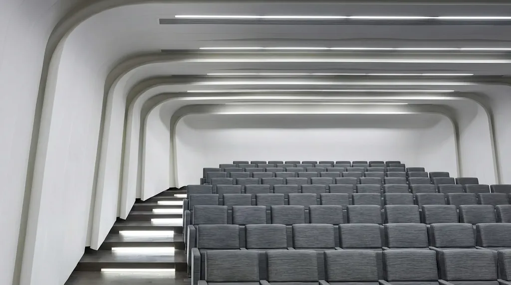 Lecture theatre - curved white ribs, linear ceiling runs and lit stair treads