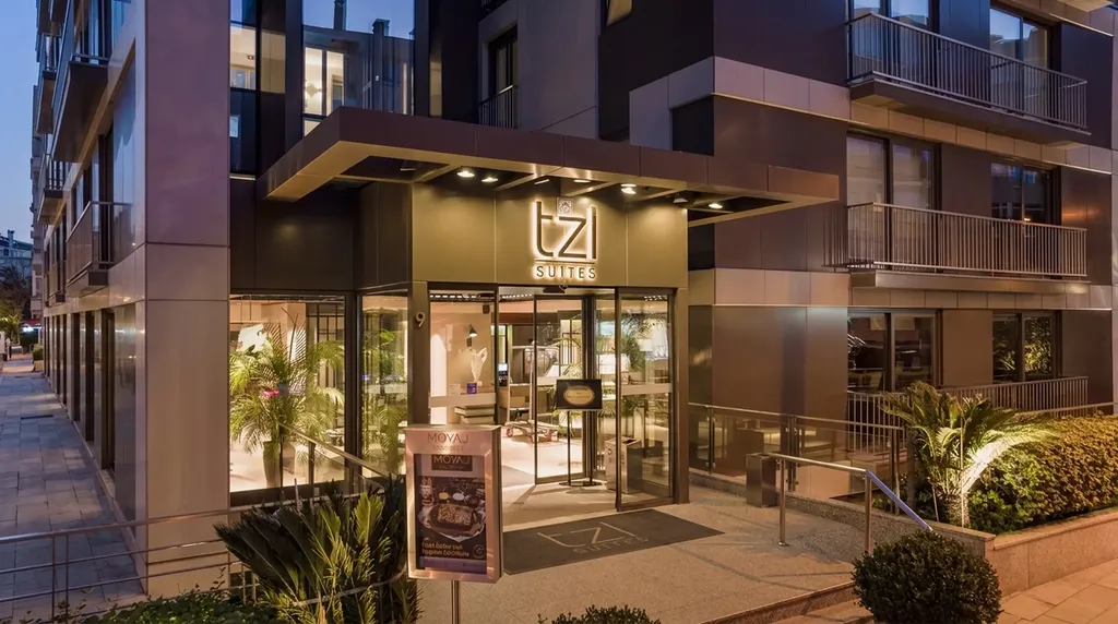 TZL Suites entrance at dusk - bronze canopy with recessed downlights and lit planting